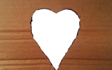 Heart shape cutout in textured brown corrugated cardboard material isolated on transparent background