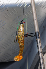 Spinnrute mit Gummifisch Shad in der Farbe Motoroil mit Stinger Drilling.