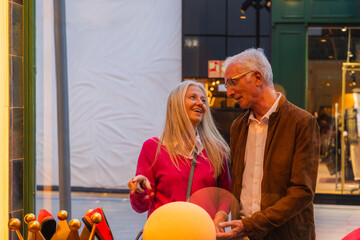 Mature couple laughing together while looking at a shop window