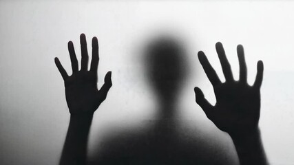 Dark silhouette of person presses hands against frosted glass creating eerie mysterious horror atmosphere suitable for thriller titles mental health concepts or dramatic transition scenes