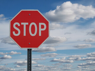 Obraz premium Stop sign on pole with blue sky and clouds background