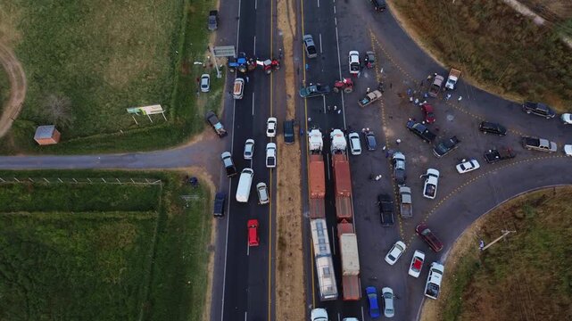 Editorial drone clip showing a highway blockade in Michoacan Mexico Farmers and tractors are stopping traffic in both directions with a Mexican flag visible during golden hour sunset
