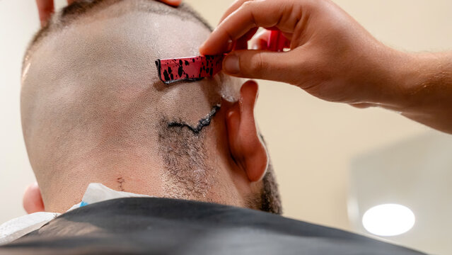 Barber using straight razor for precise haircut finish