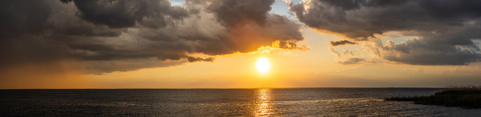 Panoramic seascape with dramatic stormy sky and sun rays
