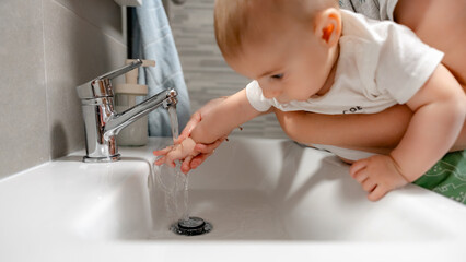 Baby learning hand washing with family assistance