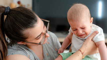 Mother soothing her upset infant at home