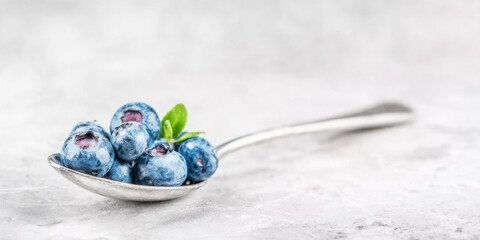 Blueberries filling a silver teaspoon, highlighting natural freshness, healthy snacking, and abundant antioxidants for a balanced diet