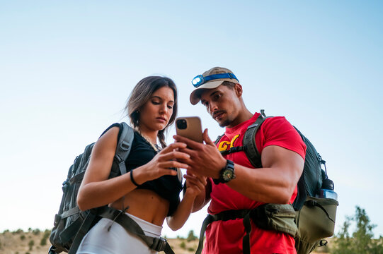 Couple hiking in sunny Red Canyon with smartphone