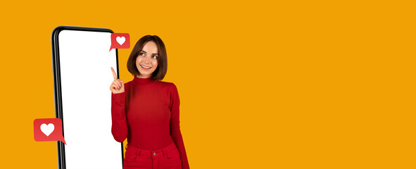 A smiling woman in a red outfit stands next to a large smartphone, pointing at the blank screen....