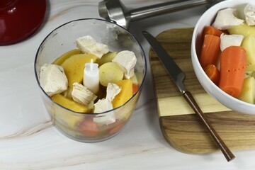 Blending vegetables with meat. Cooked chicken breast potatoes carrots swede parsnips and added broth.