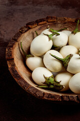 white mini eggplant, in a wooden bowl, on the table, close-up.