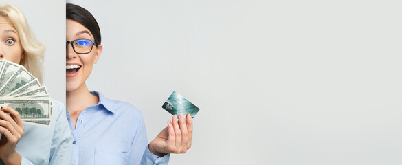 Two business professionals share a joyful moment, displaying cash and a credit card. They appear excited about a financial achievement. The scene conveys a sense of celebration and success.