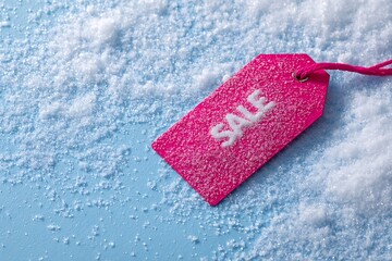 Pink sale tag lying in white snow