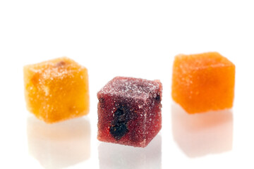 Three different colored cubes of marmalade candy are shown on a white background