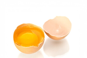 An egg is cracked open, revealing its yellow yolk