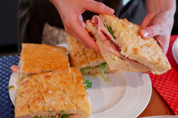 A woman making homemade focaccia sandwiches  with ham, mozzarella cheese, and pesto sauce