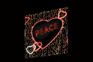 Red Christmas lights with a heart and the word "peace" inside in English  on a street in Madrid, Spain.