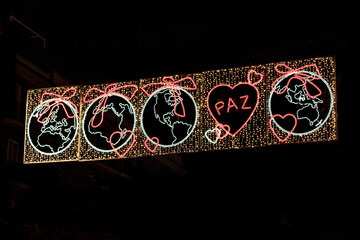 Christmas lights with a world map and a heart with the word "peace" in Spanish, on a street in Madrid, Spain.