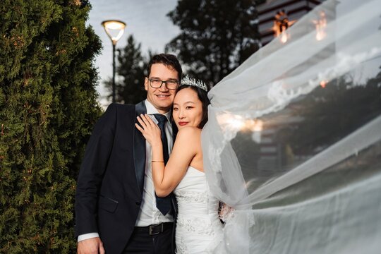 Diverse couple smiling, celebrating multicultural wedding outdoors - Powered by Adobe