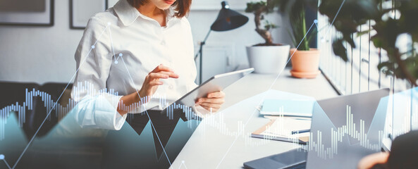 In a bright office, a freelancer focuses on business tasks using a digital tablet. She browses applications and replies to emails, managing tasks efficiently in a productive environment.