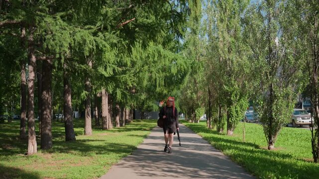 messenger on walk, man delivering package through park path, white messenger navigating city park with parcel in hand, caucasian individual carrying package along green urban corridor pathway