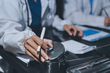 Two doctors and a female nurse meet at a table in the hospital, collaborating on medical tasks using laptops and computers