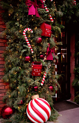 Festive outdoor decoration with red mailboxes for Santa&rsquo;s letters, candy canes, large ornaments, and pine branches adorned with lights, creating a cozy and magical holiday atmosphere. Selective focus.
