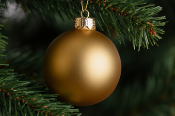 A close-up of a golden Christmas ornament hanging from a Christmas tree, symbolizing festive joy and holiday cheer.