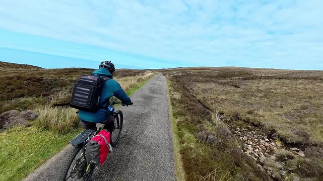 active senior man riding her electric mountain bike on the moor landscape of Rua Reidh point near Gairloch in Scotland, UK