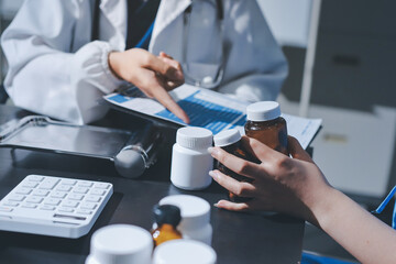Female doctor holding a medicine bottle is checking the quality of medicine for any side effects the patient or not and recording patient information at the hospital. medical and health care concept