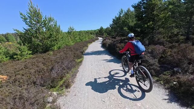 nice senior woman riding her electric mountain bike  in the highlands of Cairn Gorms National Park , Scotland, UK