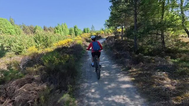 nice senior woman riding her electric mountain bike  in the highlands of Cairn Gorms National Park , Scotland, UK