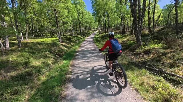 nice senior woman riding her electric mountain bike  in the highlands of Cairn Gorms National Park , Scotland, UK