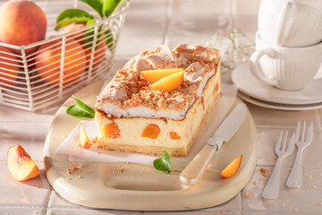 Fresht and sweet peach cheesecake served on white kitchen.