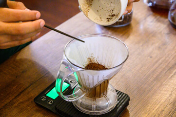 Hand pouring fresh coffee grounds for pour over brewing