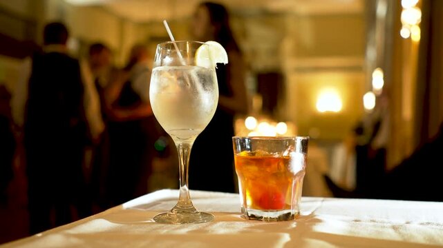 alcoholic drinks on table at a wedding reception party during the night with  people in the background