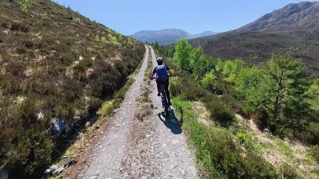 nice senior woman riding her electric mountain bike  in the highlands of Glen Affric Nature reserve, Scotland, UK
