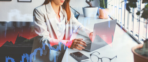 A calm and concentrated European businesswoman in formal wear types on a laptop in a modern office. She is immersed in her tasks, surrounded by plants and a contemporary work environment.