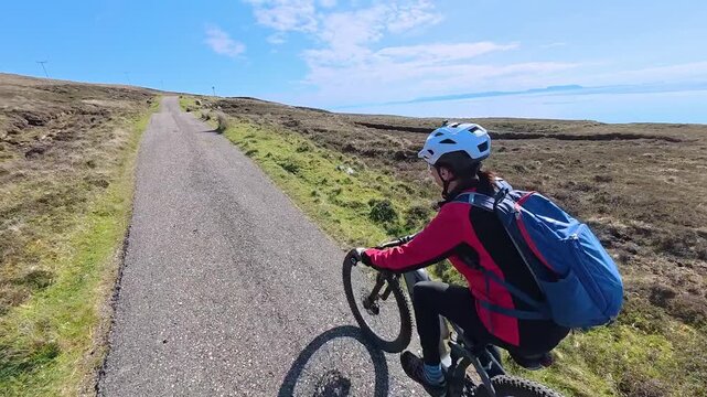 active senior woman riding her electric mountain bike on the moor landscape  of Rua Reidh point  near Gairloch  in Scotland, UK