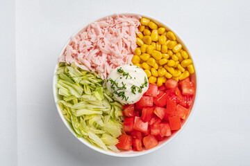 A vibrant bowl filled with lettuce, tomatoes, corn, and turkey, topped with creamy dressing