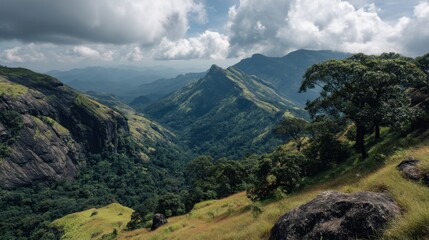 Clouds cover the sky while sunlight breaks through over mountains and valleys. Green hills stretch across the landscape creating a rich view. Nature is displayed in the afternoon light.