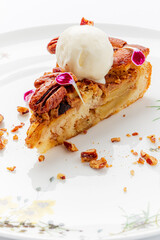 Warm apple pie slice adorned with crunchy nuts, creamy ice cream, and beautiful edible petals