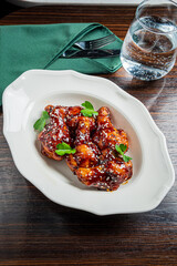 Delicious chicken wings coated in rich sauce, fresh herbs on top, perfect for sharing at dinner
