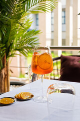 A colorful citrus drink rests on a table, surrounded by fresh greenery and sunlight