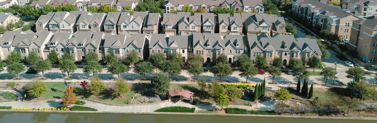 Panorama aerial townhouses arranged symmetrically along central driveway, with canal-side walkways and landscaped trees, suburban density and organized residential planning, Flower Mound, TX
