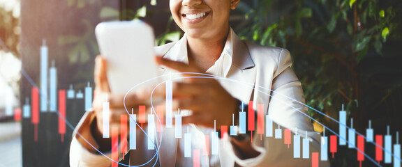 A business professional smiles as they use their smartphone, engaged in analyzing financial data trends.