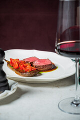 Enjoying a delectable meal featuring tender meat paired with vibrant tomatoes and red wine