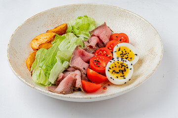 A vibrant salad with fresh lettuce, juicy tomatoes, roast beef, and creamy boiled eggs