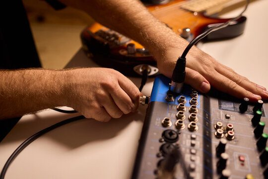 Closeup of tactile controls and vibrant patch cords in studio, Adjusting analog sequencing equipment with bright cables and warm ambient lighting in home studio