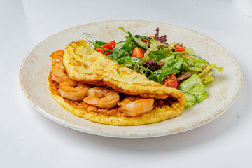 Savory shrimp omelette paired with vibrant greens and tomatoes showcases a tasty meal